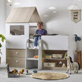 Child reading a book in a playhouse bed with toys and books around